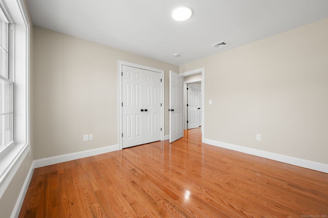 unfurnished bedroom featuring baseboards, visible vents, a closet, and light wood-type flooring