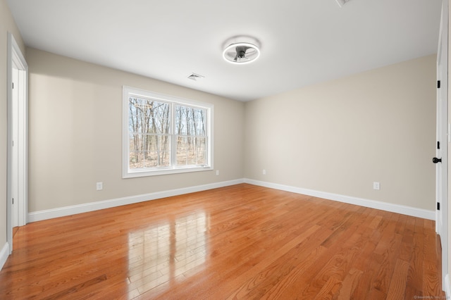 unfurnished room featuring light wood-style flooring, baseboards, and visible vents