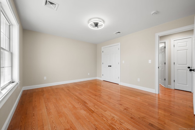 empty room with visible vents, baseboards, and light wood finished floors