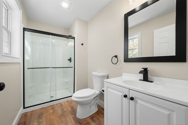 full bath featuring toilet, a stall shower, wood finished floors, baseboards, and vanity