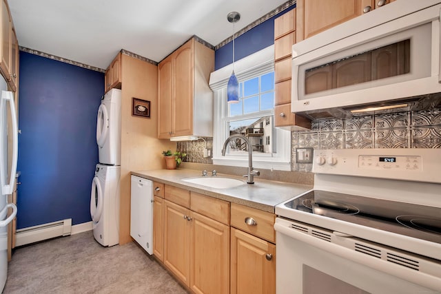 kitchen with white appliances, stacked washer / drying machine, decorative light fixtures, light countertops, and a sink