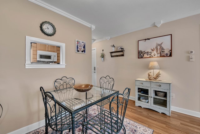 dining area with light wood finished floors, baseboards, and ornamental molding