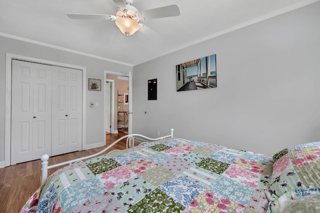 bedroom featuring baseboards, a ceiling fan, wood finished floors, crown molding, and a closet