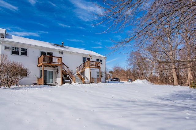 snow covered rear of property featuring a deck and stairs