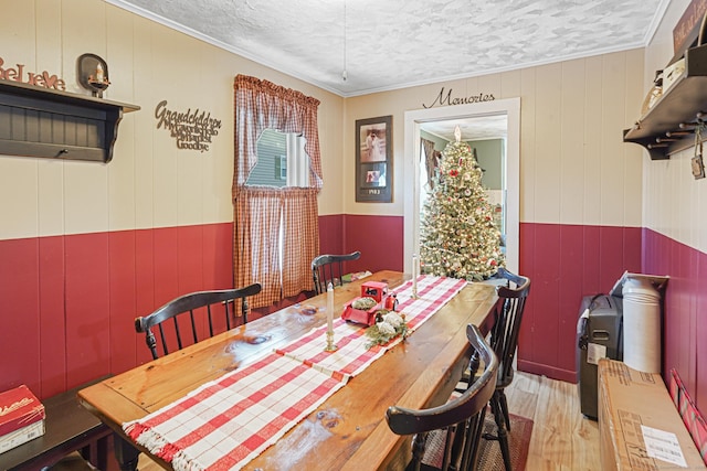 dining space with a textured ceiling, light wood-style flooring, and crown molding