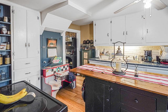 kitchen with light wood-style flooring, a ceiling fan, white cabinetry, electric range oven, and tasteful backsplash