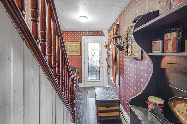 interior space featuring a textured ceiling, stairway, dark wood finished floors, and wallpapered walls