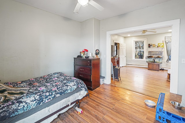 bedroom with a baseboard heating unit, wood finished floors, and a ceiling fan