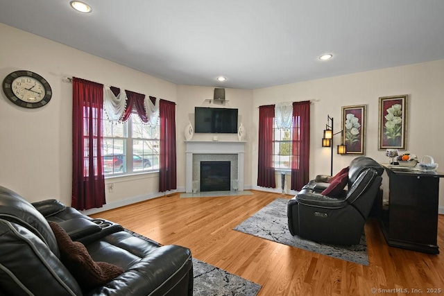 living area with recessed lighting, a fireplace, baseboards, and wood finished floors