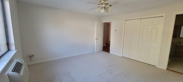 unfurnished bedroom with ceiling fan, a closet, a wall mounted AC, and baseboards