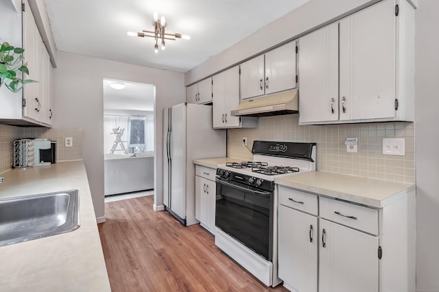 kitchen featuring gas range oven, light countertops, white cabinetry, a sink, and under cabinet range hood