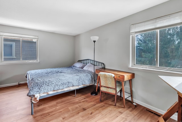 bedroom with light wood-type flooring, visible vents, and baseboards