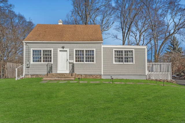 view of front of house featuring a front yard, roof with shingles, fence, and a chimney