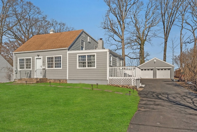 view of front of house with a shingled roof, an outdoor structure, a detached garage, a front lawn, and a chimney