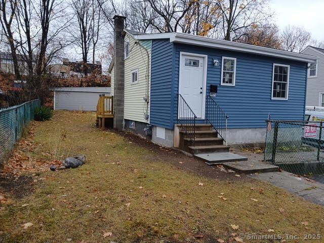 exterior space with entry steps, fence, a chimney, and a front yard