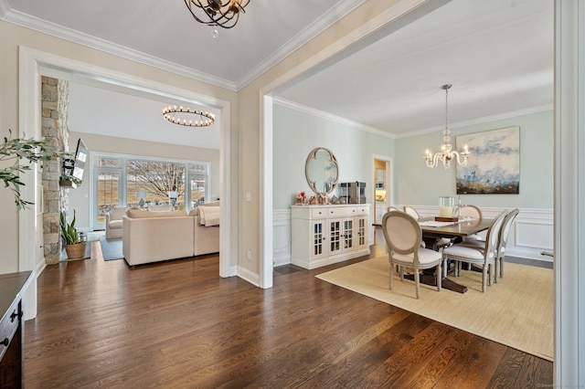 dining space with a chandelier, wainscoting, dark wood-type flooring, and crown molding