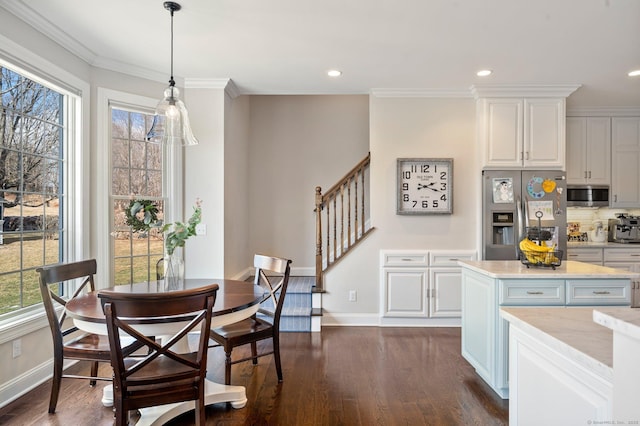 dining space featuring ornamental molding, dark wood finished floors, baseboards, and stairs