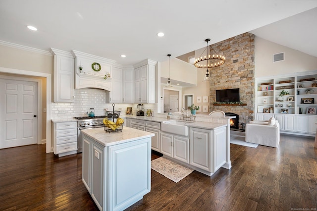 kitchen featuring pendant lighting, open floor plan, white cabinets, a sink, and a peninsula