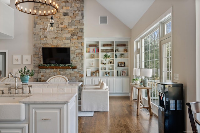 interior space with a sink, visible vents, white cabinetry, light stone countertops, and pendant lighting