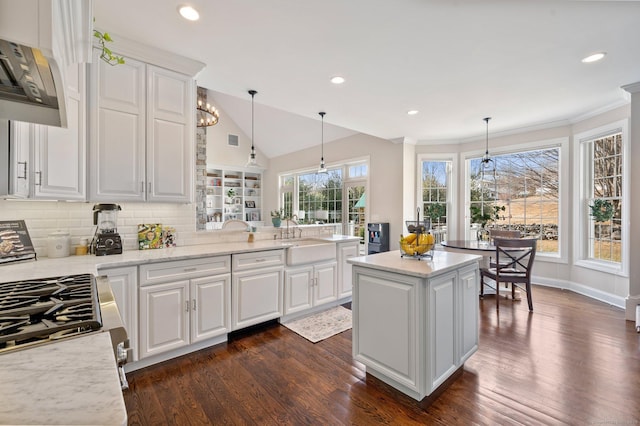 kitchen with white cabinetry, a sink, decorative light fixtures, and light stone countertops