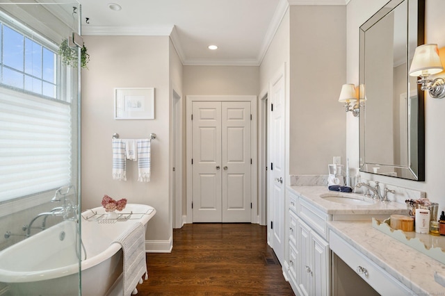 bathroom with wood finished floors, crown molding, vanity, a freestanding tub, and a closet