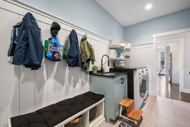 mudroom with light wood finished floors, a decorative wall, a sink, and independent washer and dryer