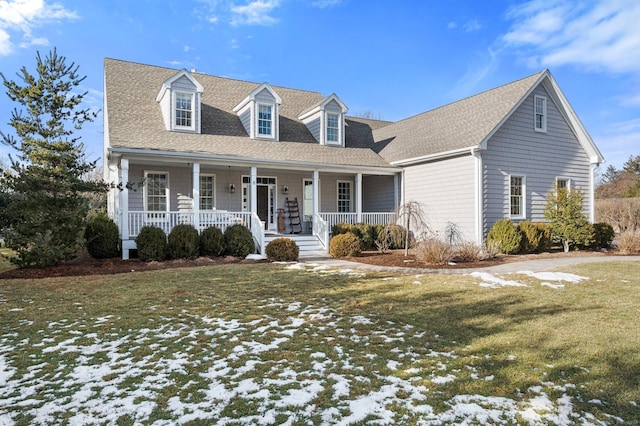 cape cod house with covered porch, roof with shingles, and a yard