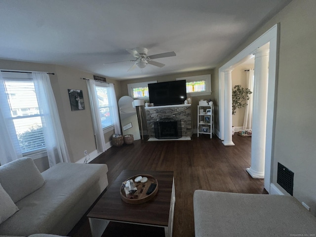 living area featuring plenty of natural light, a stone fireplace, and ornate columns