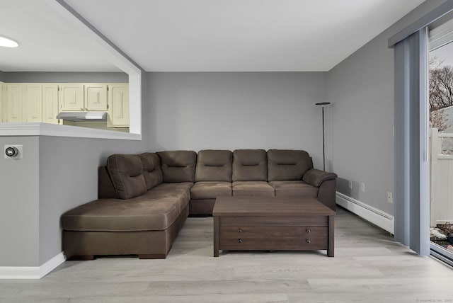 living room featuring a baseboard heating unit, light wood-type flooring, and baseboards