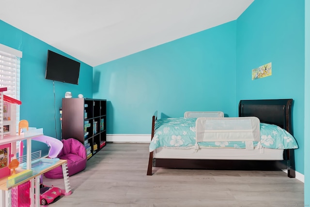 bedroom featuring baseboard heating, vaulted ceiling, baseboards, and wood finished floors