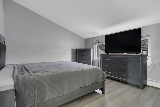 bedroom featuring light wood-type flooring, lofted ceiling, and a baseboard heating unit