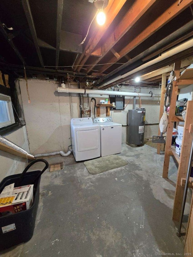 unfinished basement featuring water heater, washer and clothes dryer, and electric panel