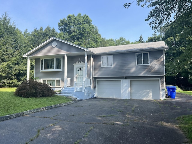 split foyer home with driveway, an attached garage, and a front lawn