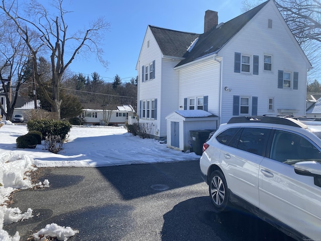 snow covered property featuring roof with shingles and a chimney