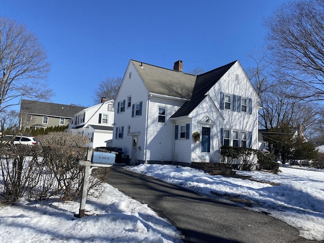 view of front of house featuring a garage, roof with shingles, driveway, and a chimney