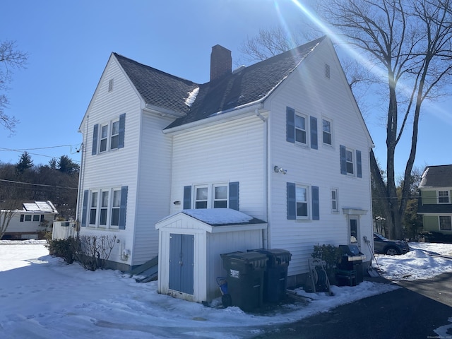 exterior space featuring a chimney and roof with shingles