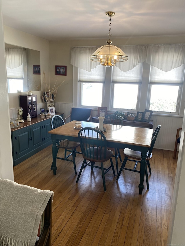 dining space featuring a wainscoted wall, an inviting chandelier, and wood finished floors