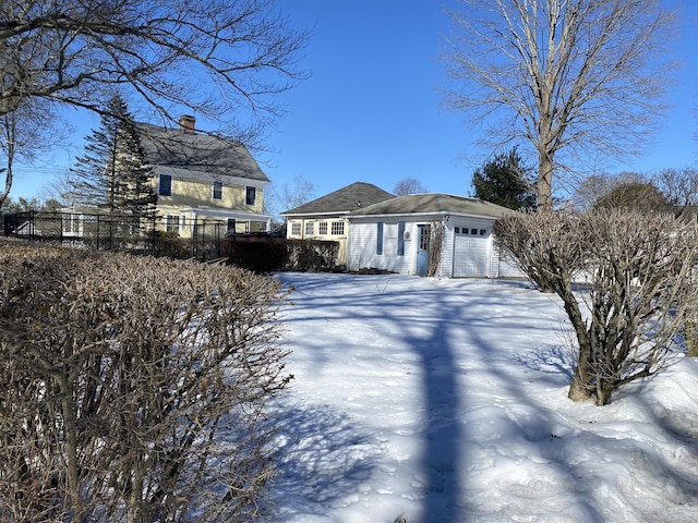 view of front of home with a chimney, an attached garage, and fence