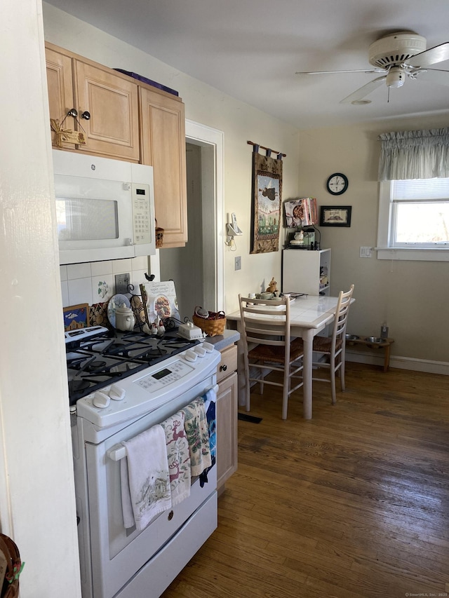 kitchen featuring dark wood finished floors, light brown cabinetry, ceiling fan, white appliances, and baseboards