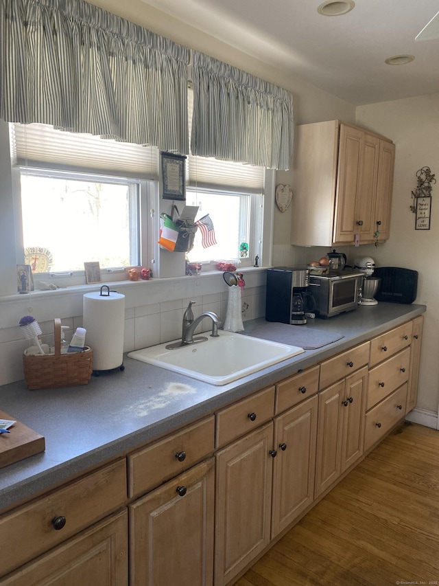 kitchen with light brown cabinetry, a sink, and light countertops