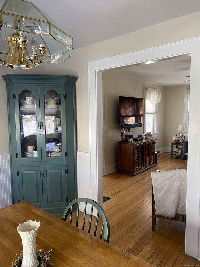 dining room featuring a chandelier, wainscoting, and light wood-type flooring