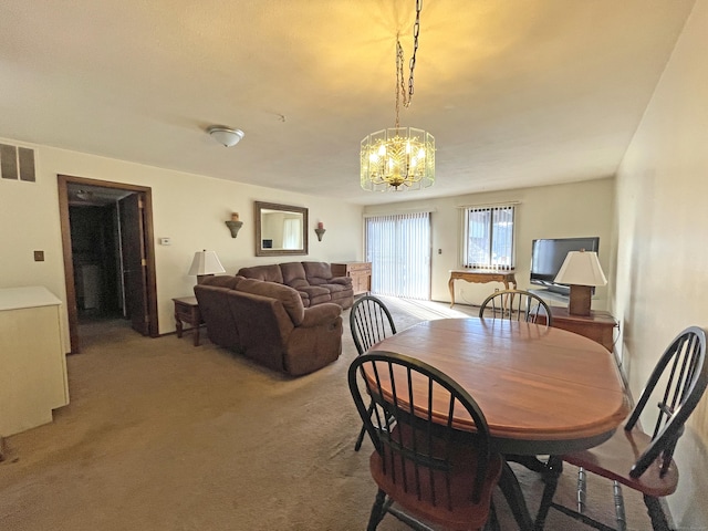 dining area featuring visible vents, a notable chandelier, and light colored carpet