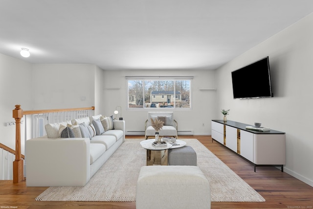 living room with a baseboard heating unit, baseboard heating, wood finished floors, and baseboards