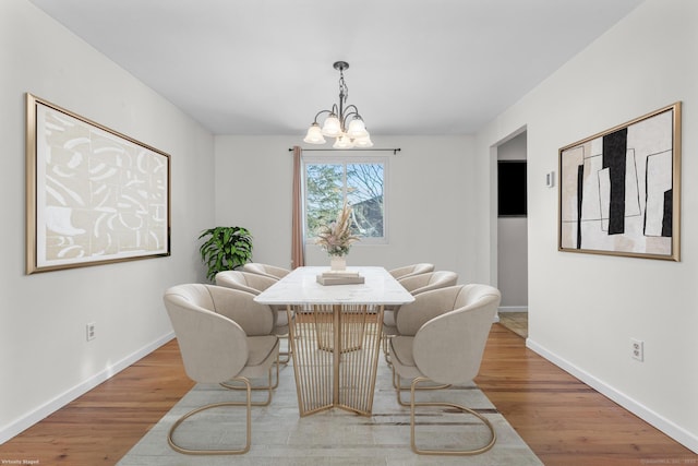 dining room with a notable chandelier, baseboards, and wood finished floors