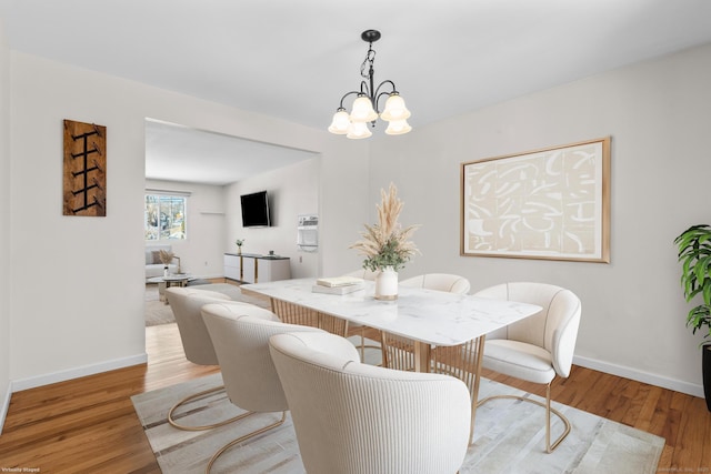 dining area with a notable chandelier, light wood finished floors, and baseboards