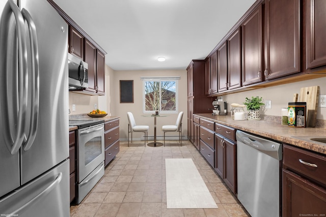 kitchen featuring stainless steel appliances, light tile patterned flooring, and dark brown cabinetry