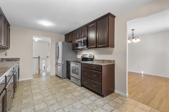 kitchen featuring appliances with stainless steel finishes, baseboards, a sink, and dark brown cabinetry