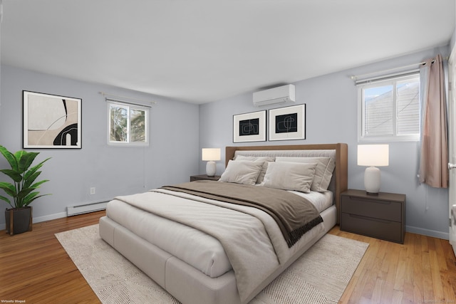 bedroom with a baseboard heating unit, an AC wall unit, baseboards, and light wood finished floors