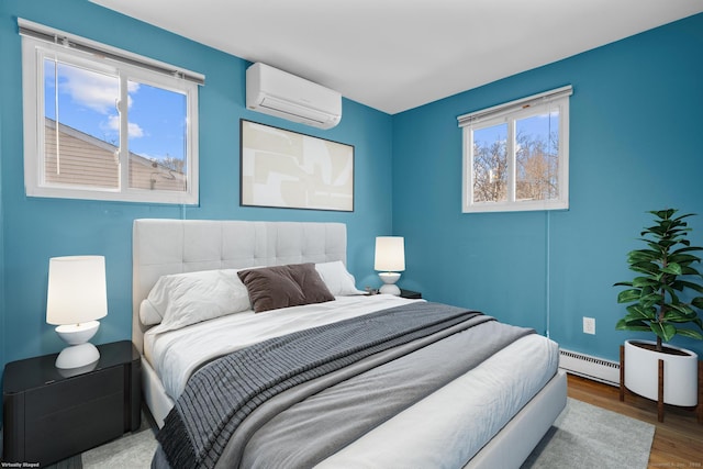 bedroom featuring a wall unit AC, a baseboard radiator, and wood finished floors