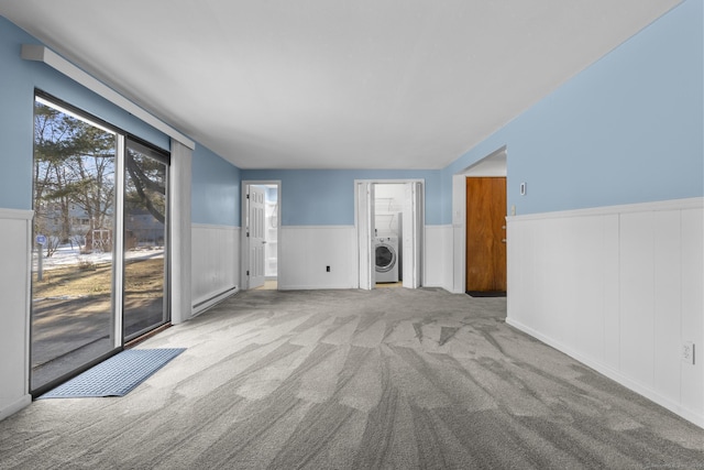 carpeted spare room featuring a wainscoted wall and washer / dryer